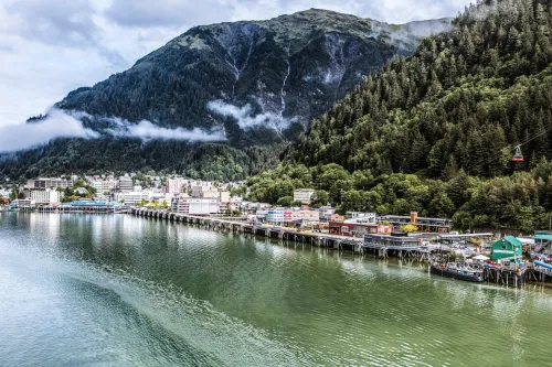 Expansive view of downtown Juneau and waterfront, Alaska. Morning, waterfalls and fog nestled in the mountains. Mount Roberts tram operating at right.