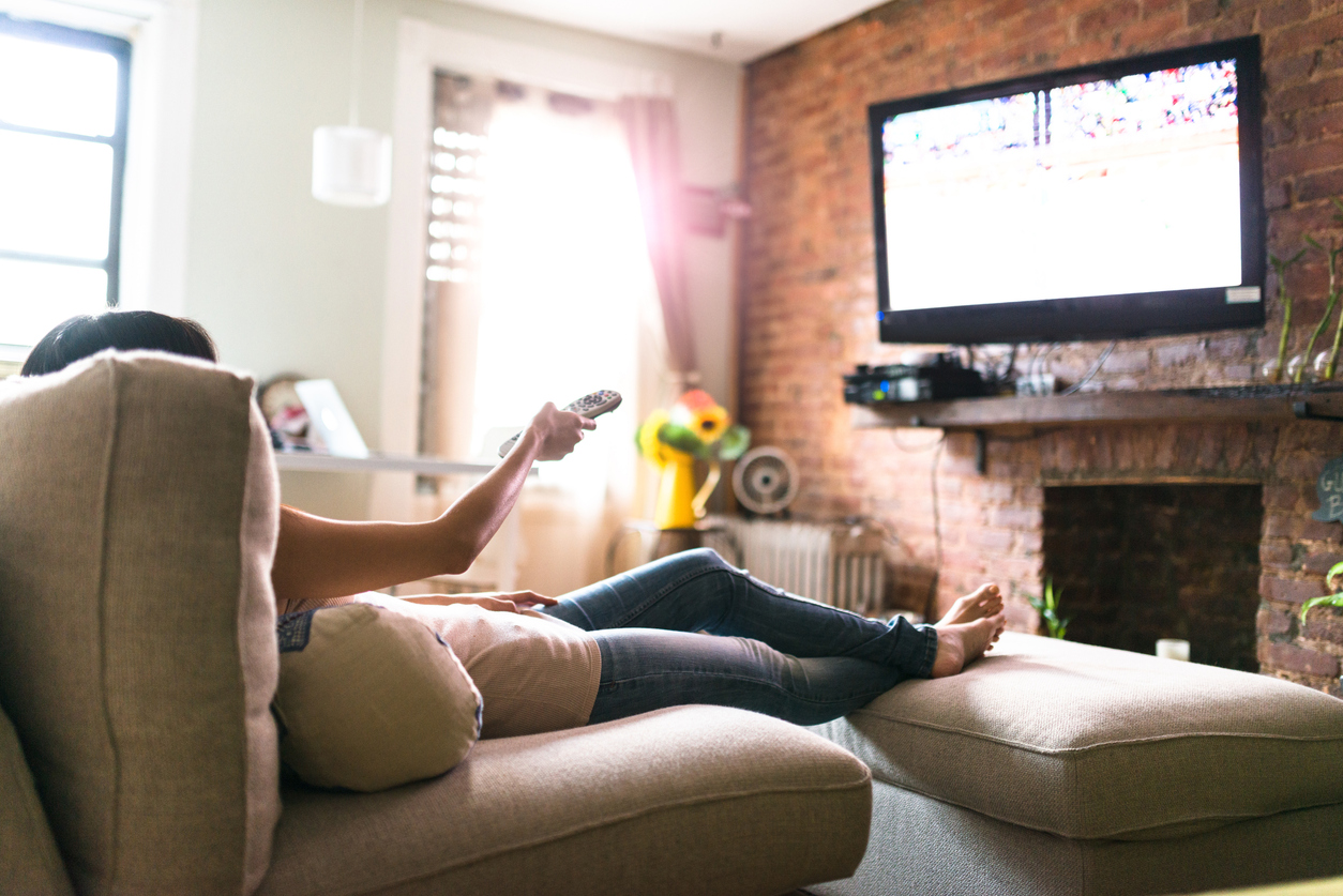 Woman sitting on a sofa watching television.