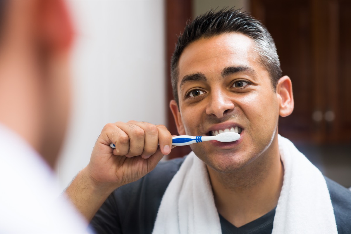 Close-up image of a man brushing the teeth in the apartment