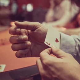 A close up of a person pulling a hidden card out of their sleeve while cheating in a casino