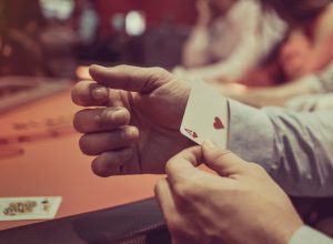 A close up of a person pulling a hidden card out of their sleeve while cheating in a casino