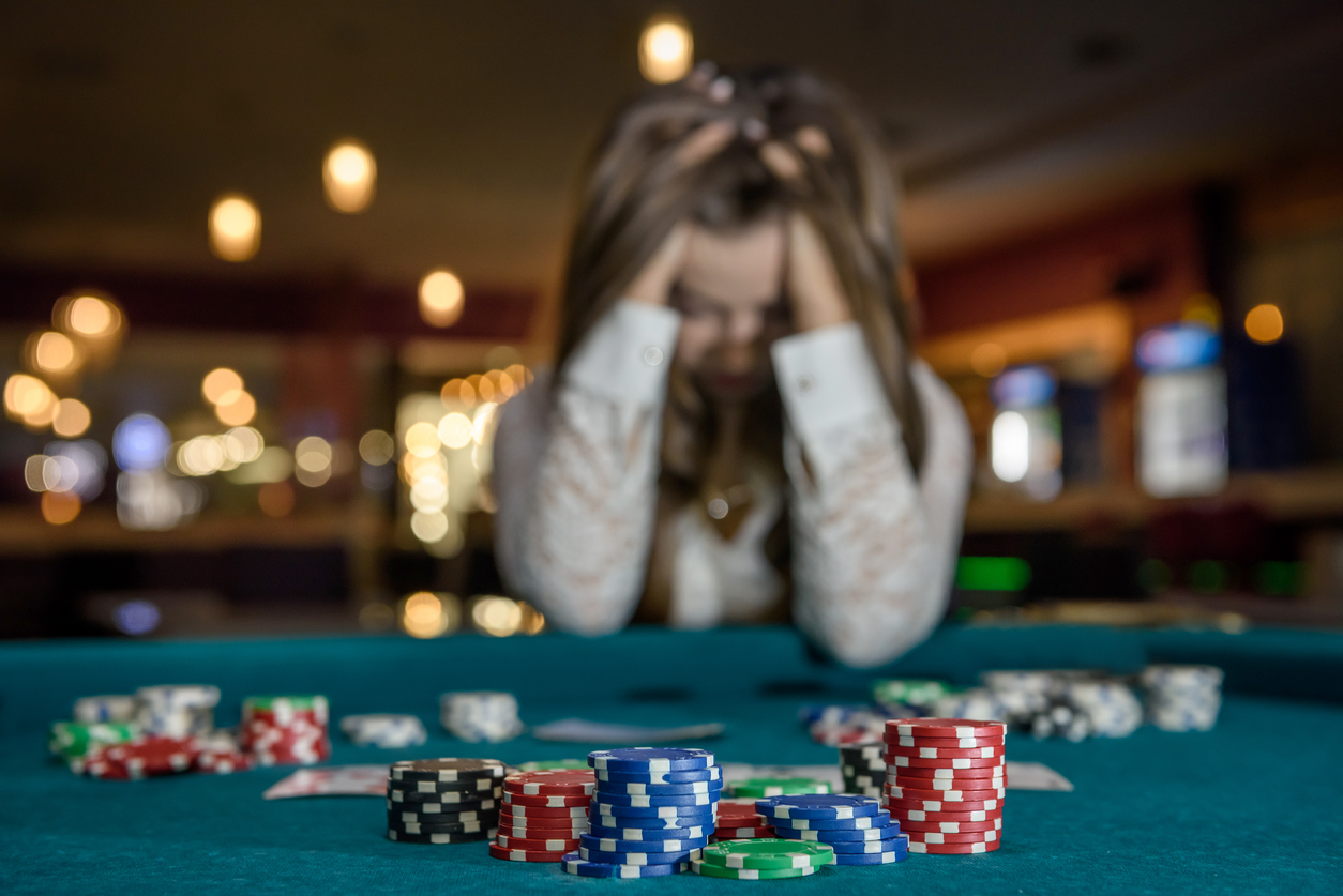 A person sitting in a casino at a table after losing a hand of poker