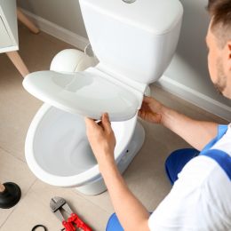 Plumber installing toilet in restroom