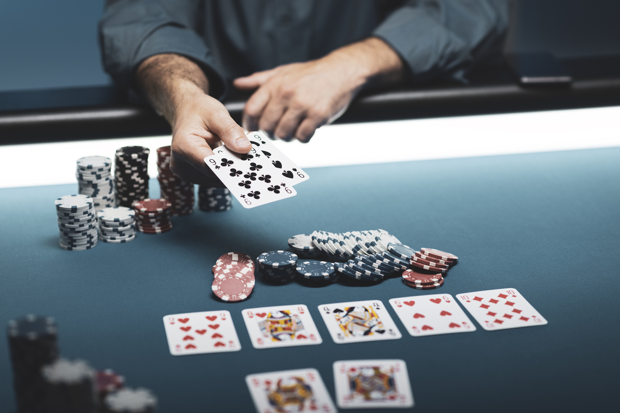 A closeup of a poker game with all cards and hands in view with chips on either side