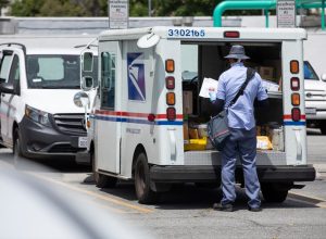 A USPS (United States Parcel Service) mail truck and postal carrier make a delivery.