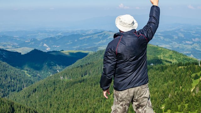 Hiker,With,Raised,Arm,In,A,Waving hand pose,Watching,A,Mountain