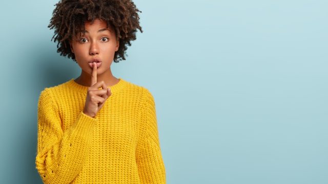 Young Black Woman Putting One Finger To Her Mouth