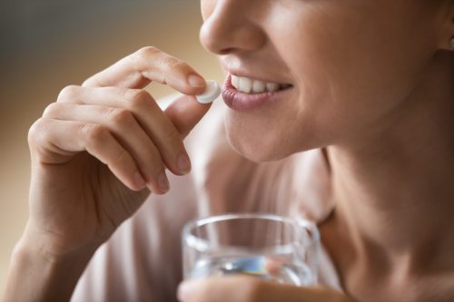Woman taking tablet with water