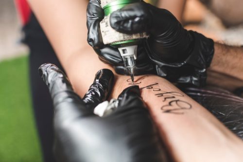 tattoo artist writing cursive name