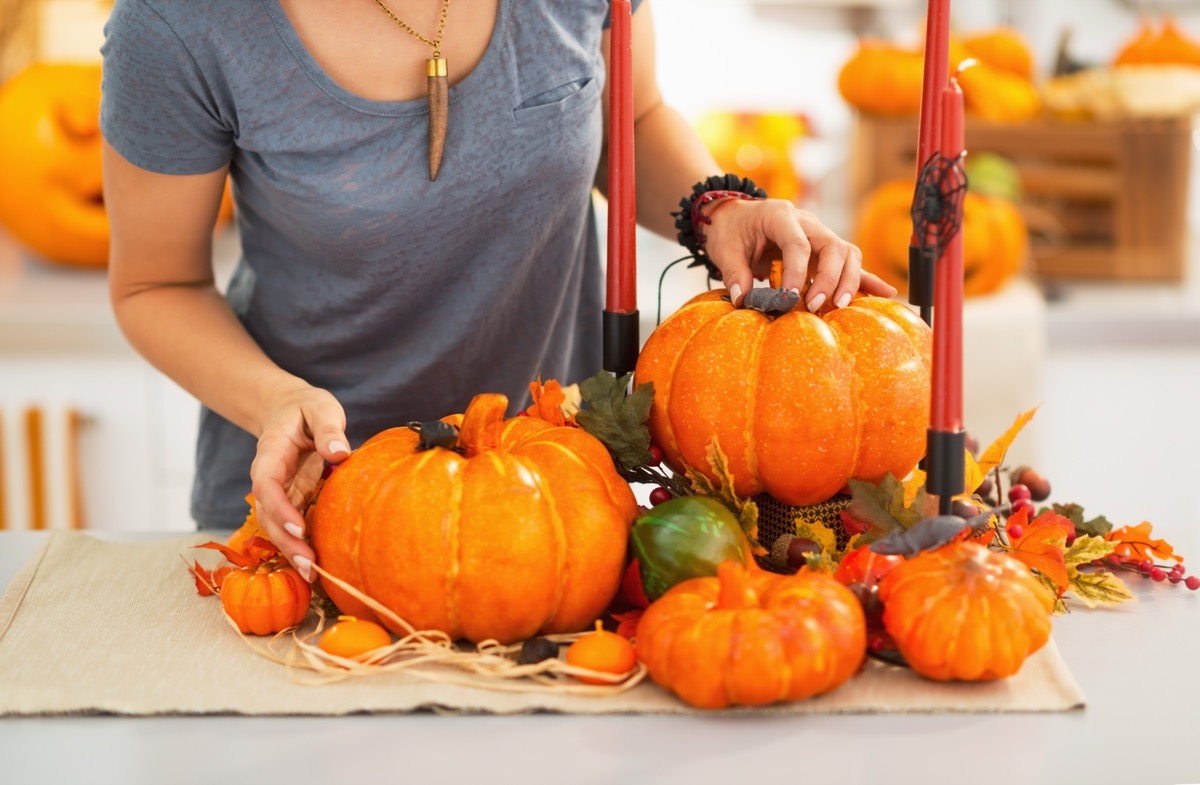 woman decorating for fall with fake pumpkins