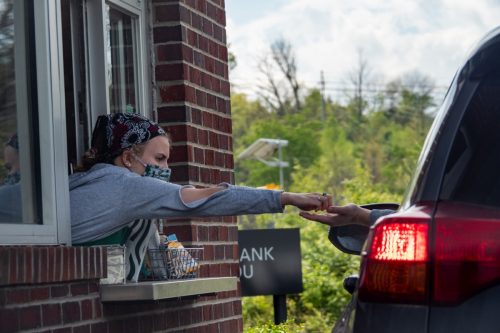 A Starbucks employee hands a customer their change as businesses begin to reopen around the country in the wake of the Coronavirus COVID-19 pandemic, Friday, May 8, 2020, in Louisville, Kentucky, United States.