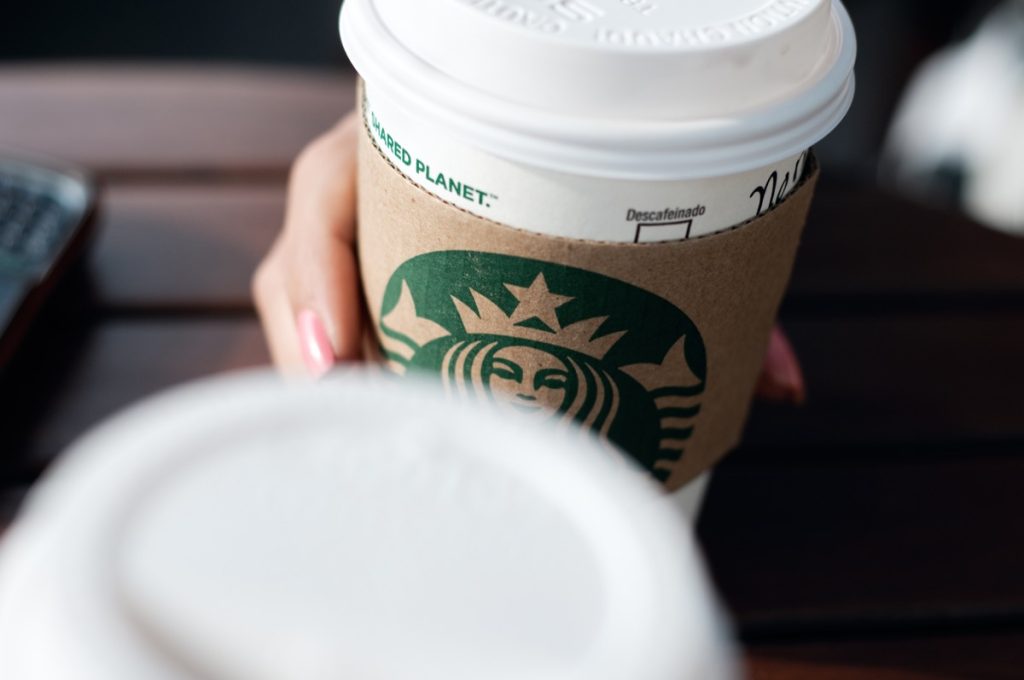 A disposable coffee cup with the Starbucks franchise logo on it.