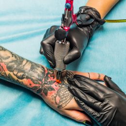 A tattoo artists putting a design on a person's hand