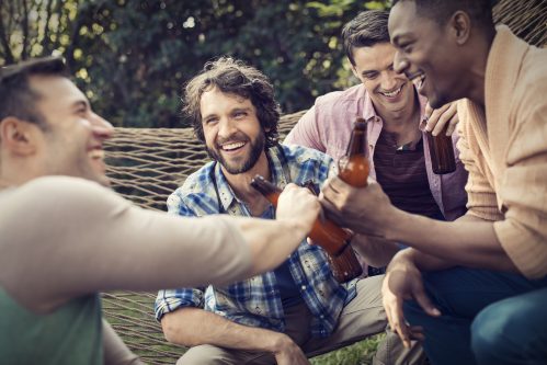group of men laughing with drinks while on a hammok - truth or dare questions for boys