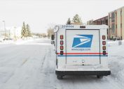 USPS, United States Postal Service, van parked on suburban street during winter with lots of snow.