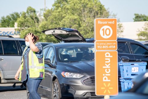 Vidalia, Georgia, USA - May 6, 2021: A Walmart employee loads grocery items to a customerâ€™s vehicle parked at a designated Pick-Up area.
