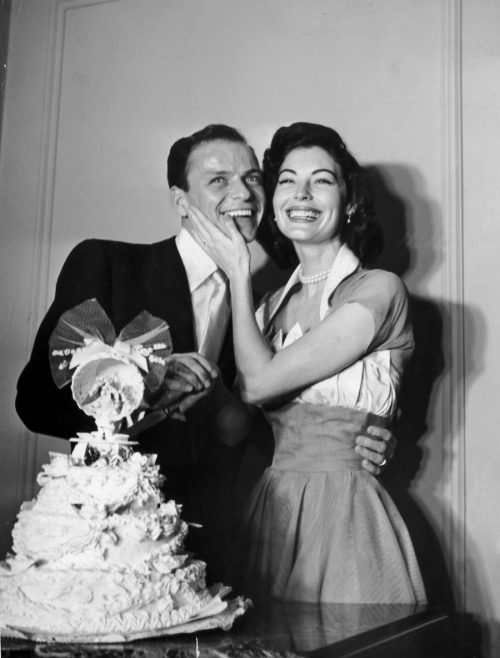 Frank Sinatra and Ava Gardner standing behind their wedding cake on their wedding day in 1951