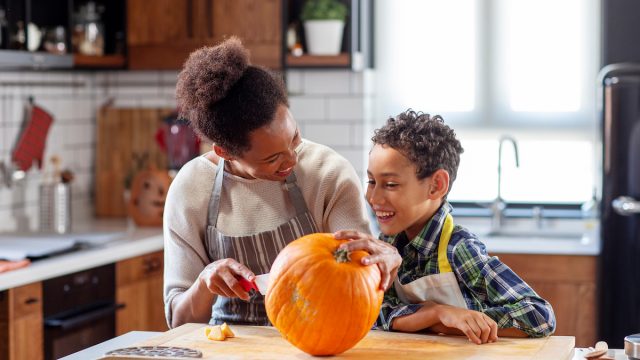 Woman with her son at the kitchen prepare pumpkin for halloween