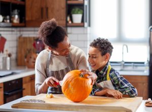 Woman with her son at the kitchen prepare pumpkin for halloween