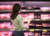 A woman shopping in the grocery store in the meat section