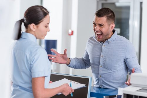 Aggressive man yelling at nurse in clinic.