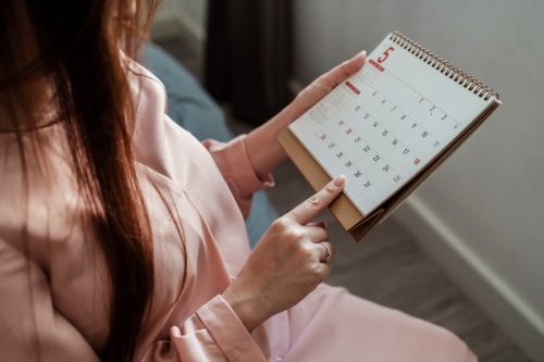Side view of woman in pink looking at date on calendar