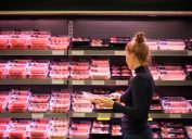A woman shopping for meat in the grocery store