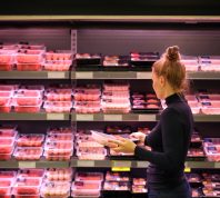 A woman shopping for meat in the grocery store