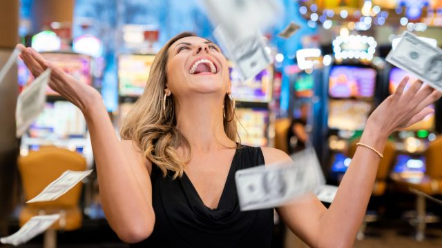 Cheerful beautiful woman excited about all the money she won at the casino throwing to the air very happy
