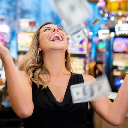 Cheerful beautiful woman excited about all the money she won at the casino throwing to the air very happy
