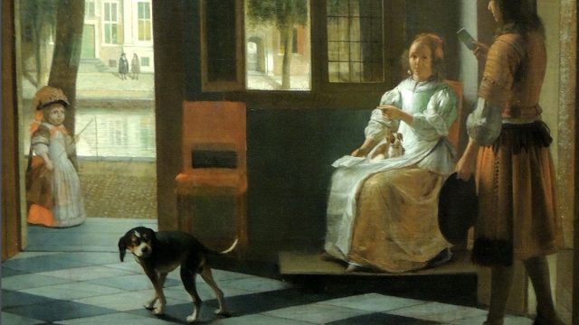 Man handing a letter to a woman in the entrance hall of a house.