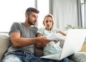 Mid adult couple having problems with home financials. Using laptop and paying bills.