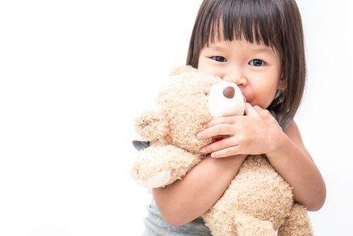 little girl holding a stuffed animal smiling