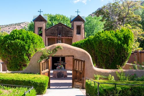 Entrance to historic adobe church El Santuario de Chimayo in Chimayo, New Mexico with mountains in the background