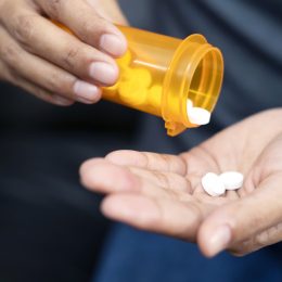 A close up of hands holding a prescription bottle and medication