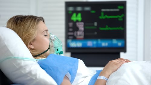 Woman in coma, heart rate falling on ecg monitor, intensive care hospital unit