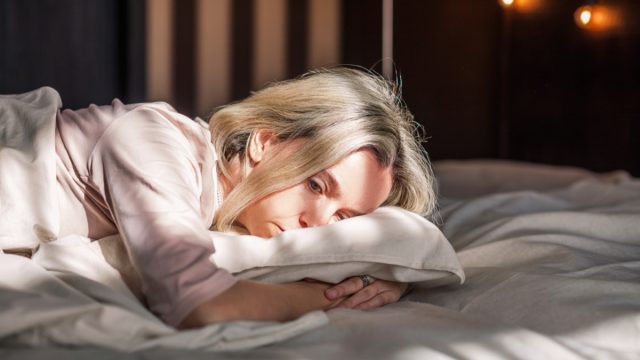Tired middle aged woman lying in bed feeling depression
