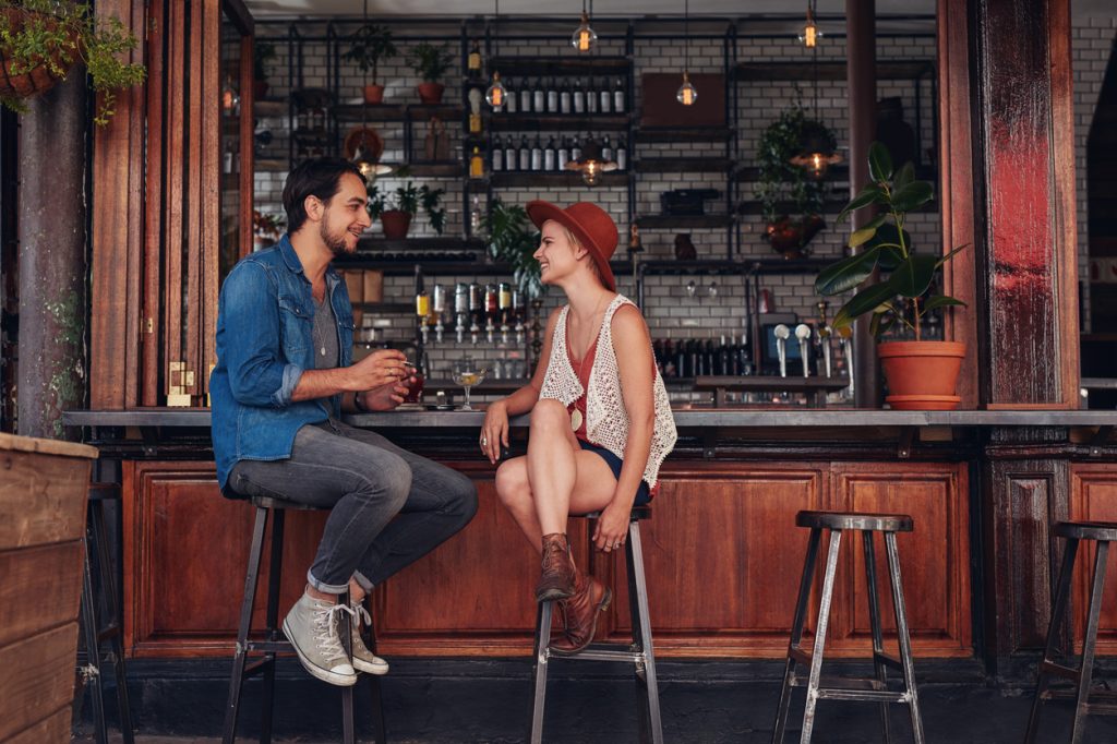 Two young patrons chatting while seated at a bar