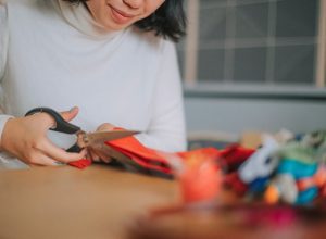 girl cutting fabric preparing cross-stitch craft at home side hustle