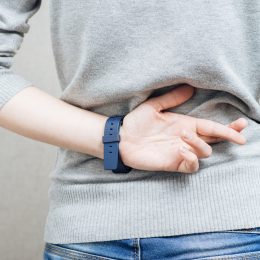Close up of a woman's back in a gray sweater with her fingers crossed behind her back.