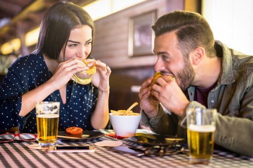 couple enjoying burger and beers at a diner