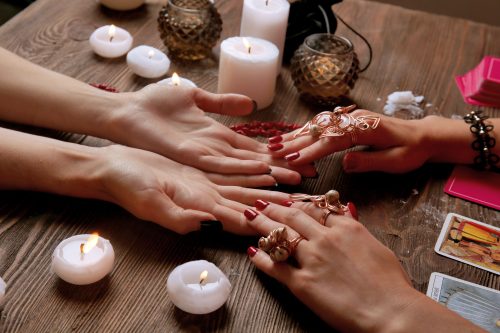 hands on table surrounded by candles