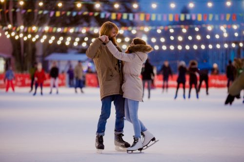 Man and woman ice skating at outdoor rink