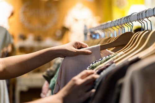 close up of woman's hands while she sifts through clothing on the rack