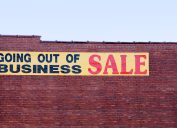 A "going out of business" sale sign hanging on the side of a brick building