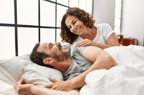 woman whispering a good morning message to her husband in bed