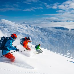 A group of three skiers schussing down a slope