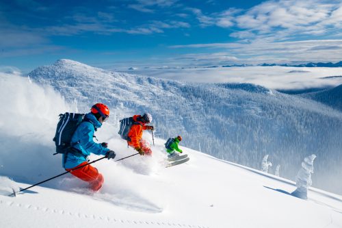 A group of three skiers schussing down a slope