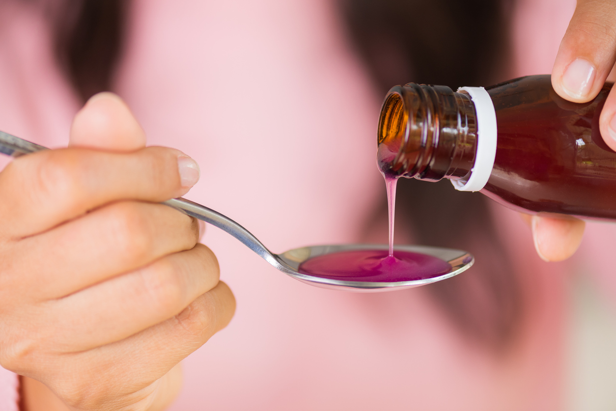 Medicine being poured into a spoon.