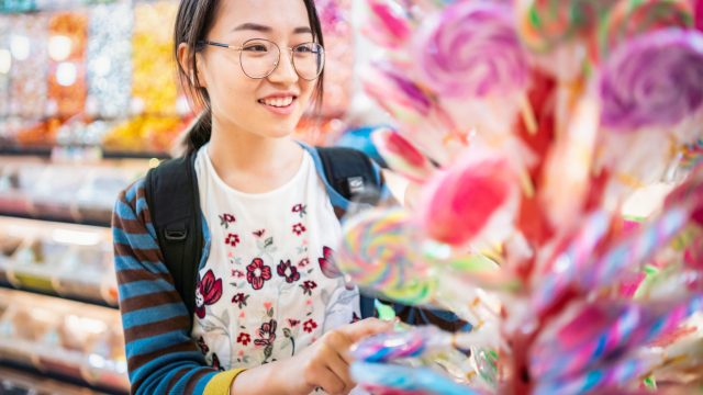 Asian girl choosing lollipops in a candy store.